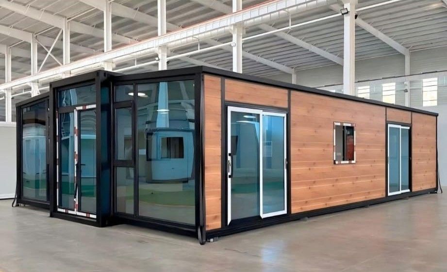 Edificio modular moderno con revestimiento de madera y grandes ventanales de cristal en el interior de un almacén.