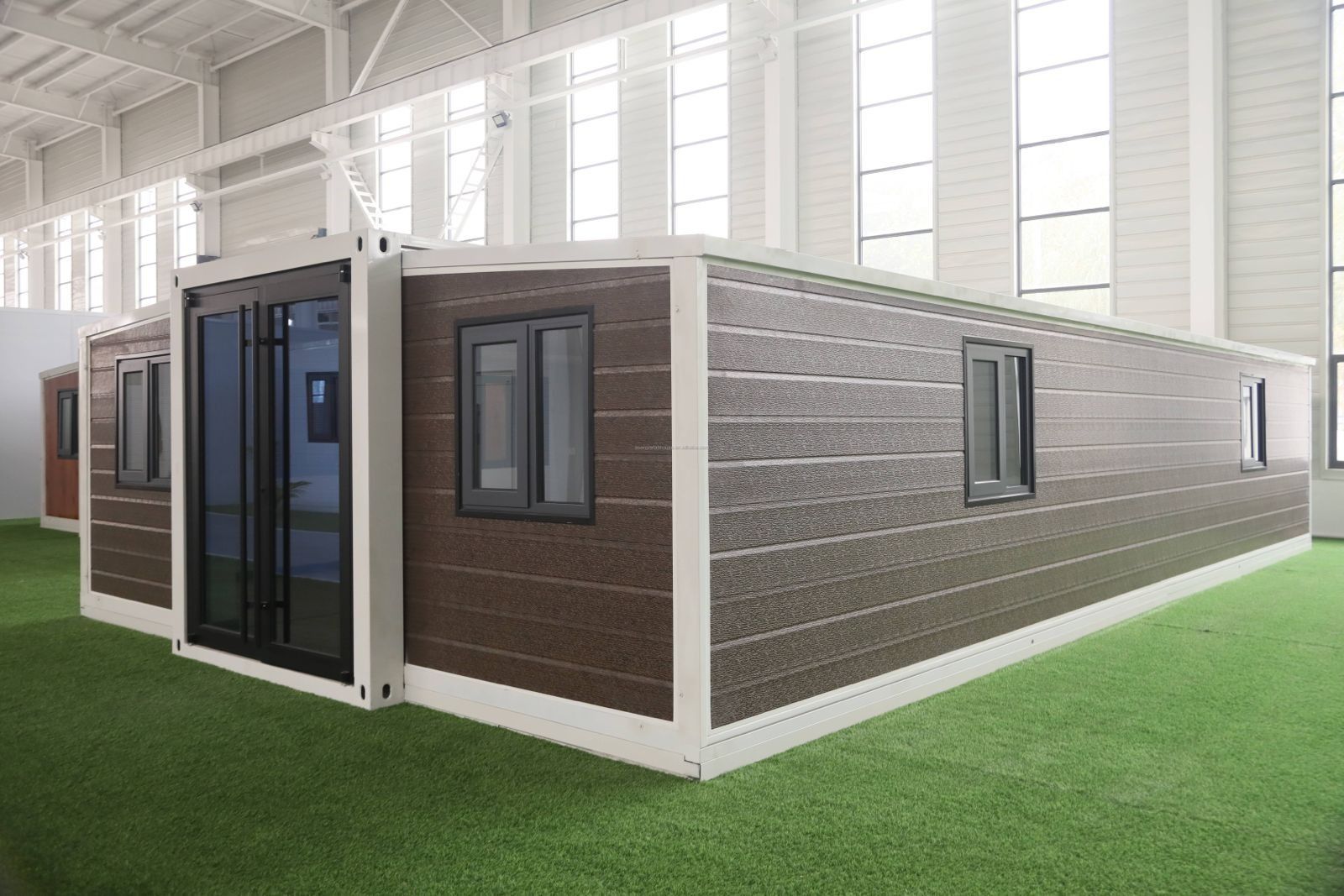 Edificio modular moderno con revestimiento gris y puertas de cristal con marcos negros