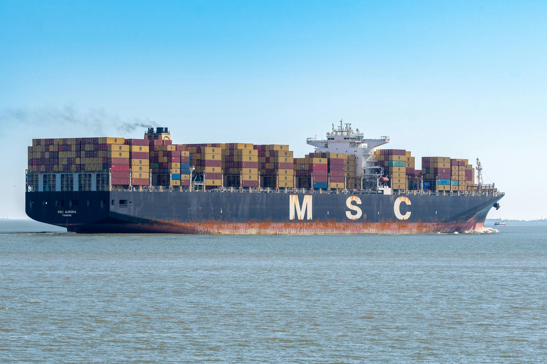 Un gran buque portacontenedores de MSC, cargado con contenedores apilados, navega en aguas azules y tranquilas.