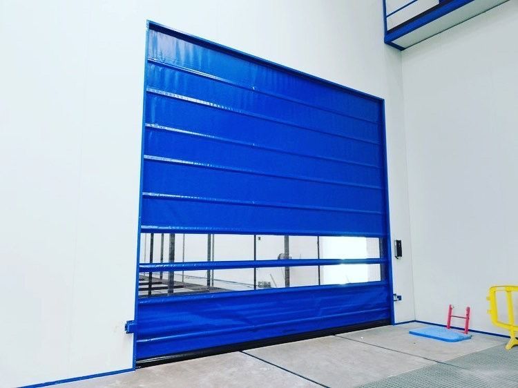 Una puerta de garaje azul está situada al costado de un edificio.