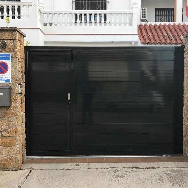 Una puerta negra está situada delante de una casa.