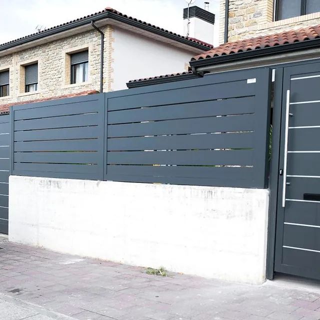 Una casa con una valla y una puerta delante de ella.