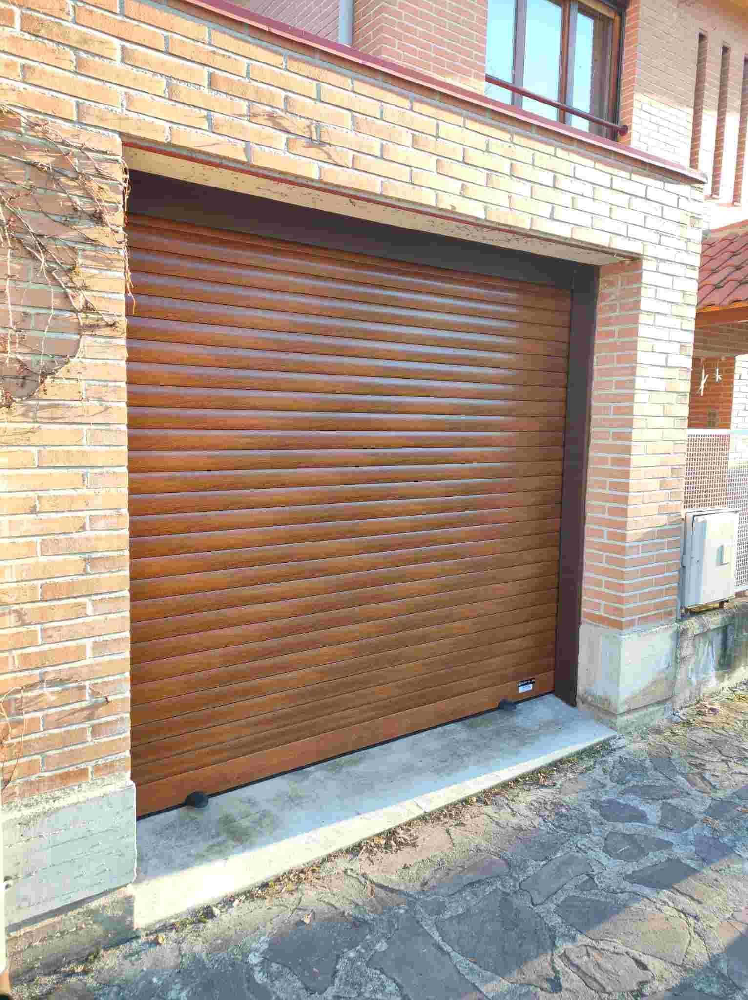 Una puerta de garaje de madera está situada delante de un edificio de ladrillo.