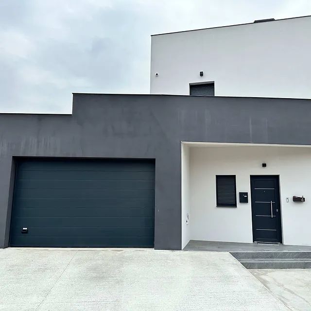 Una casa blanca con una puerta de garaje negra y una puerta negra