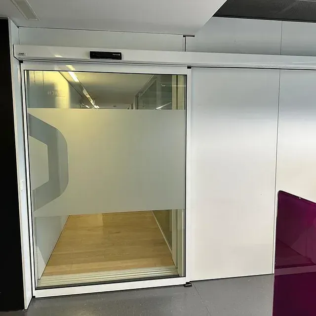 Una puerta corrediza de vidrio con una silla morada delante de ella.