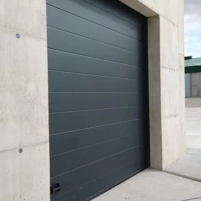 Una puerta de garaje gris está sentada al costado de un edificio.