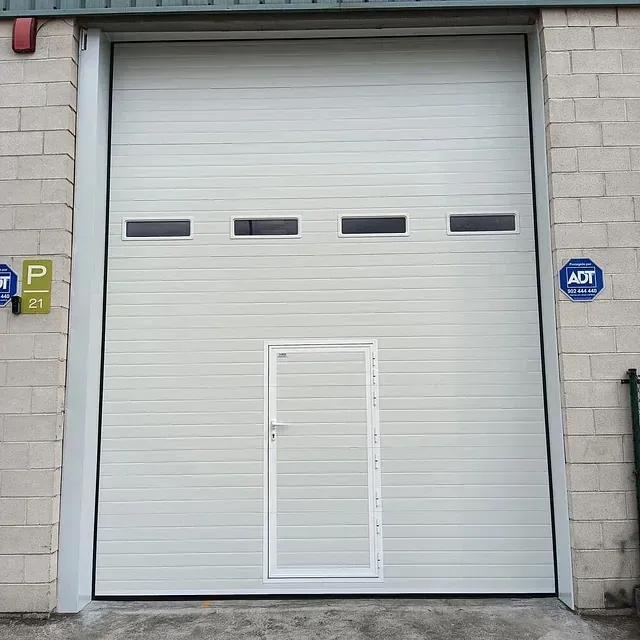 Una gran puerta de garaje blanca con una pequeña puerta debajo.