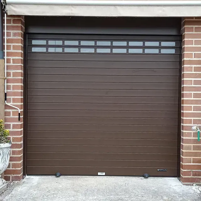 Una puerta de garaje marrón está frente a un edificio de ladrillos.