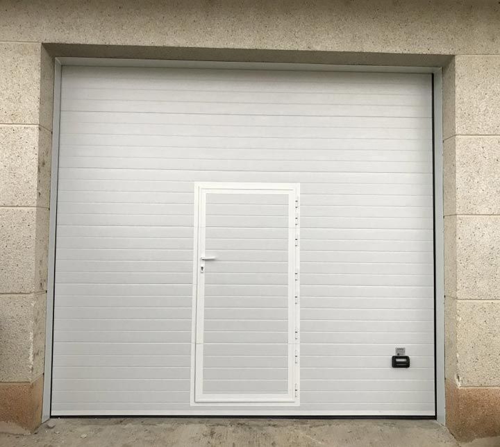 Una puerta de garaje blanca con una pequeña puerta debajo.
