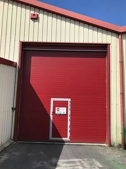 Una gran puerta de garaje roja con una pequeña puerta debajo.