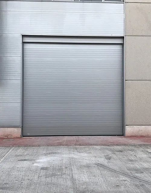 Una puerta de garaje gris está sentada al costado de un edificio.