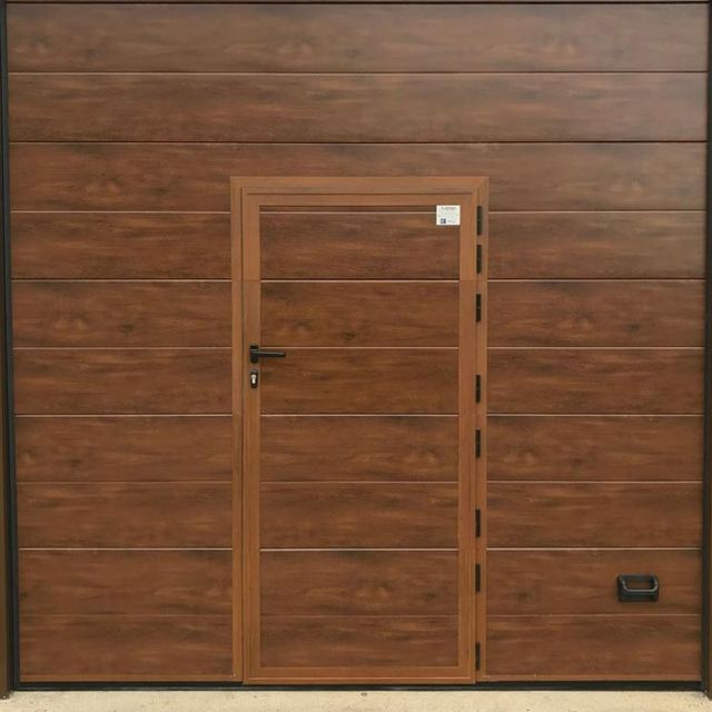 Una puerta de garaje de madera con una pequeña puerta debajo.