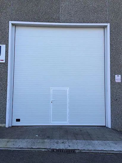 Una puerta de garaje blanca con una pequeña puerta en el medio.