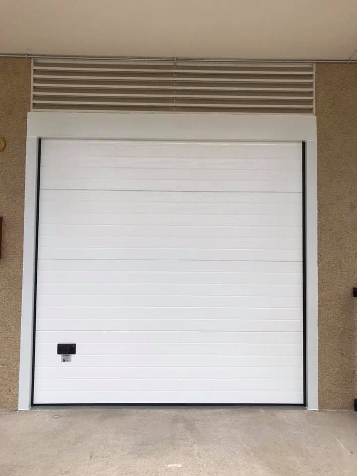 Una puerta de garaje blanca con una manija negra está abierta.