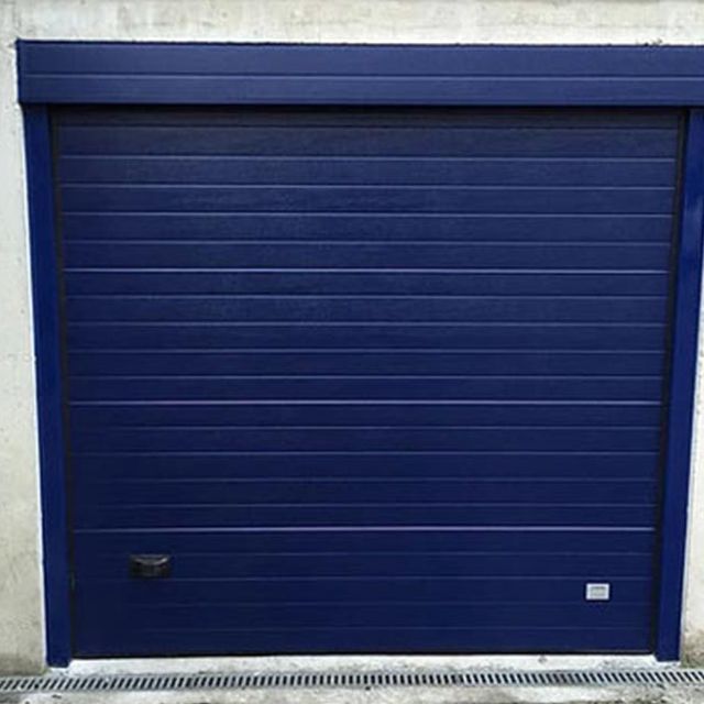 Una puerta de garaje azul está situada al costado de un edificio.