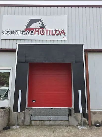 Una puerta roja con un cartel encima que dice carnicas mutiloa