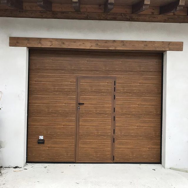 Una puerta de garaje de madera con una puerta debajo.