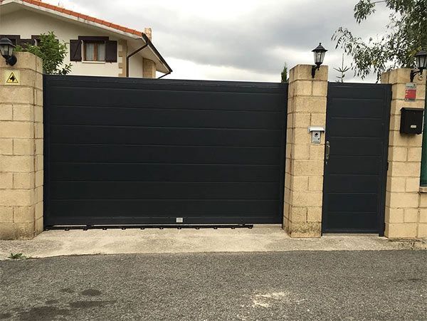 Una puerta corrediza negra está frente a una casa.