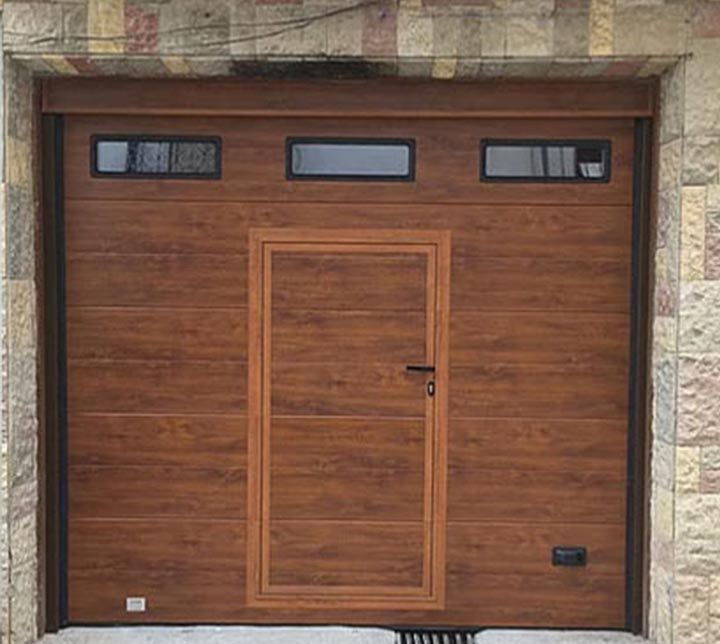 Una puerta de garaje de madera con dos ventanas y una puerta.