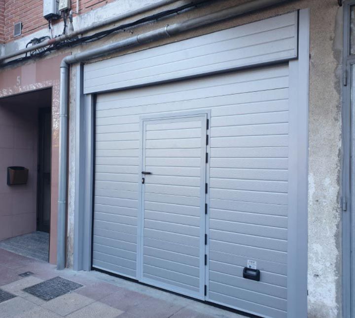 Una puerta de garaje gris con una pequeña puerta debajo.