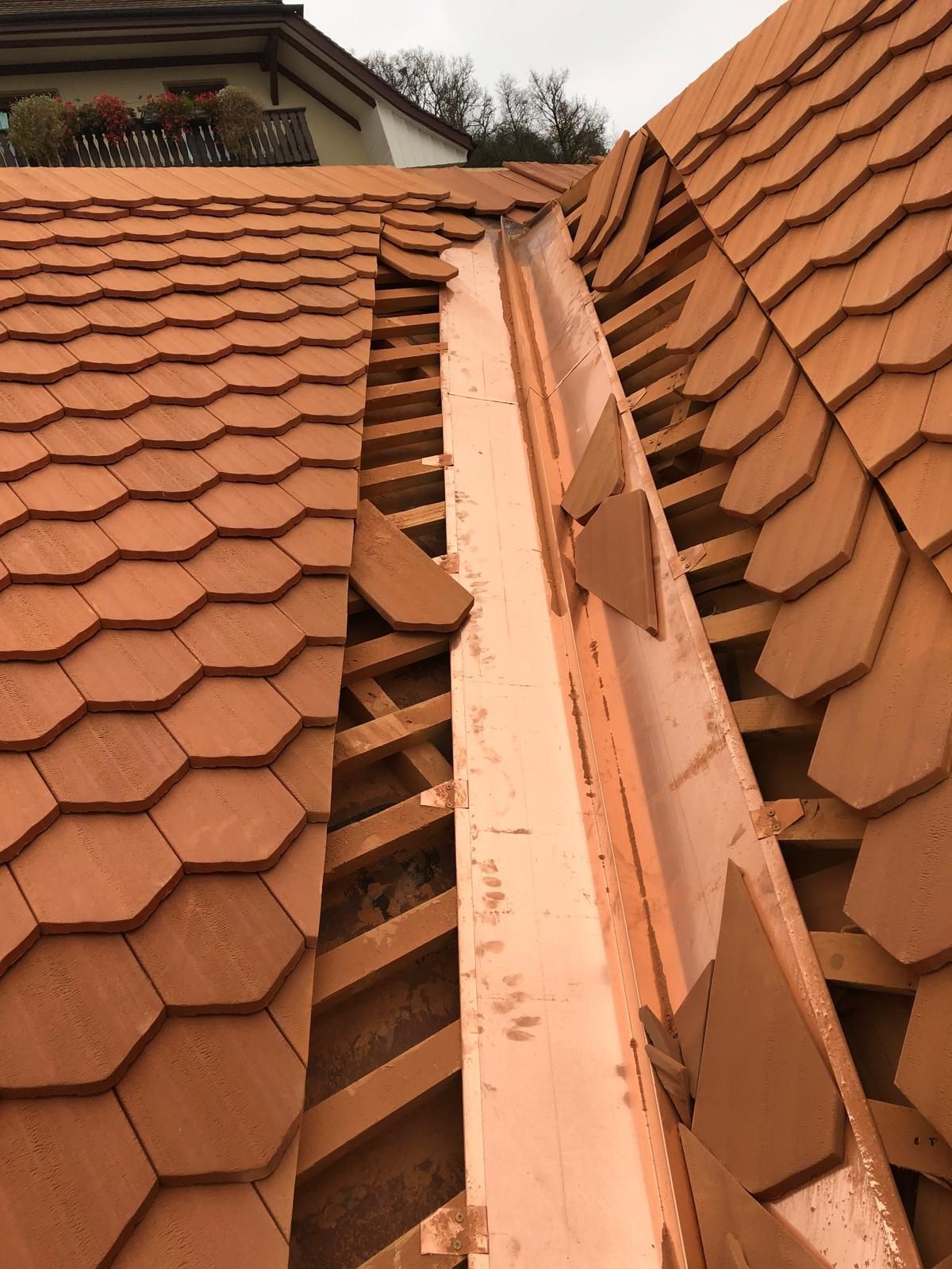 Eine Nahaufnahme eines Dachs mit Ziegeln und einer Kupferdachrinne.