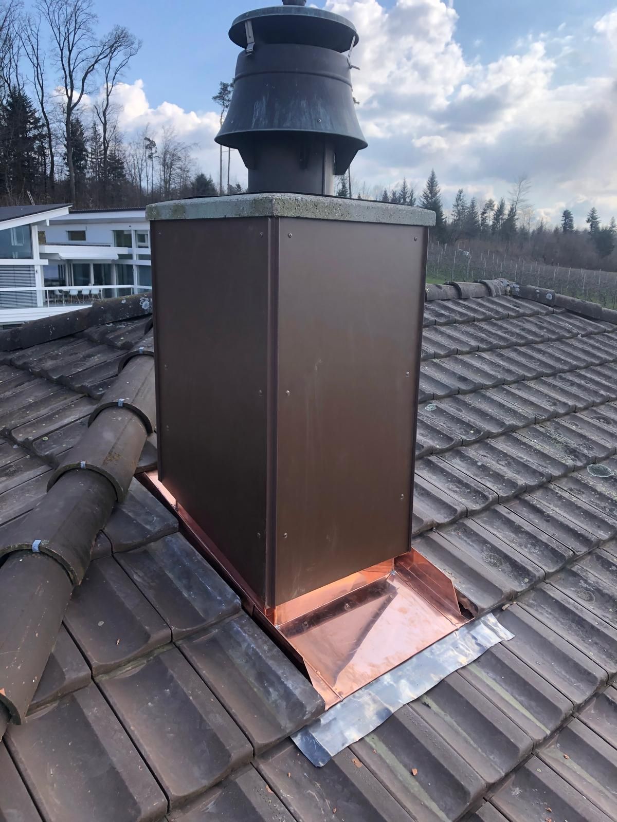 Auf einem Ziegeldach sitzt ein Schornstein.