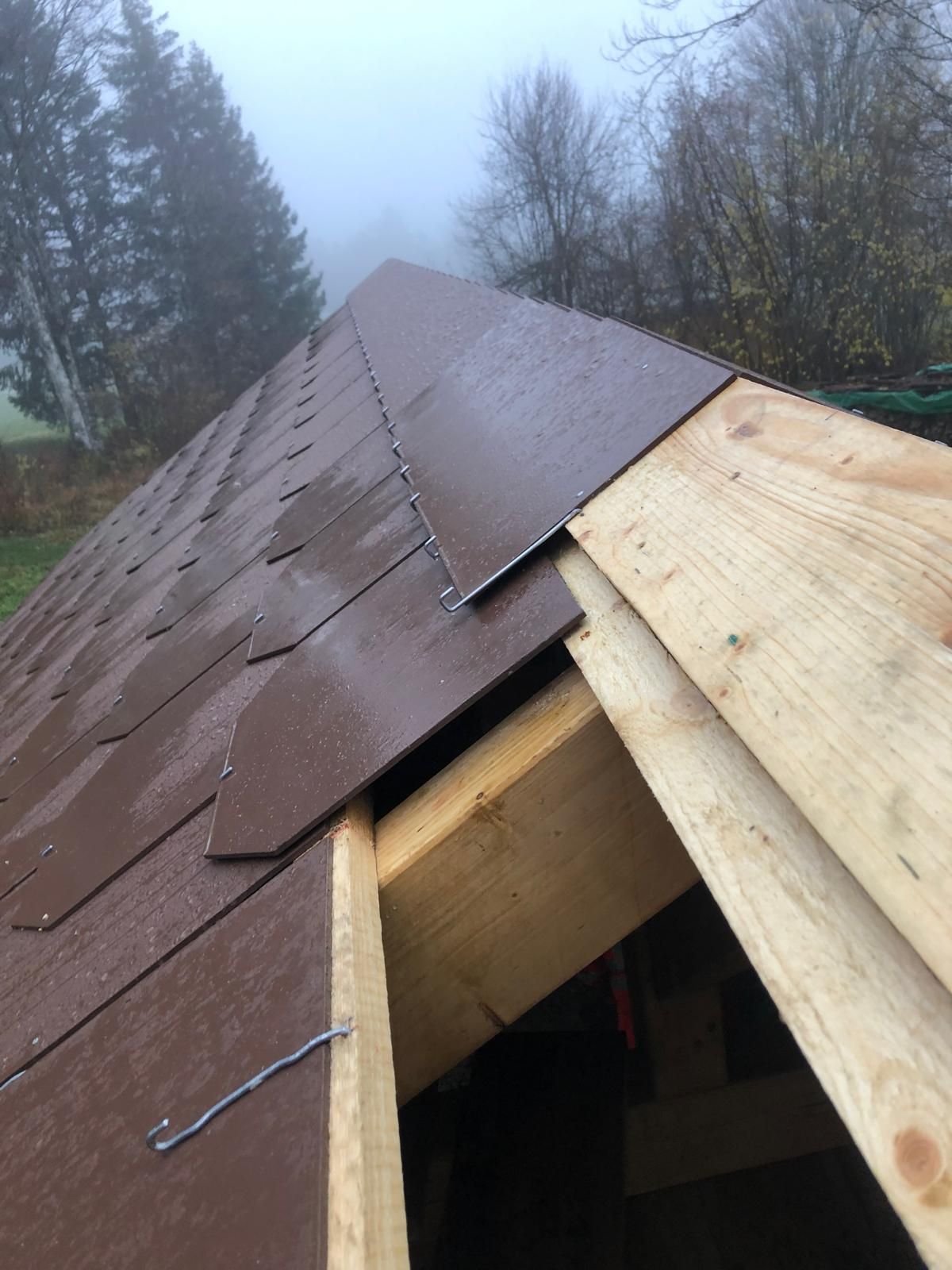 Es wird ein Dach mit Holzbalken und Schindeln gebaut.