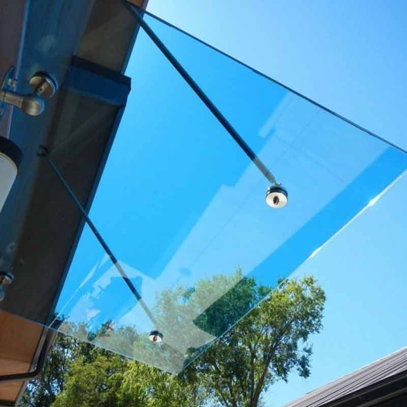 Schiebetür aus Glas mit mattierten horizontalen Paneelen und Edelstahlbeschlägen, die einen Raum mit Möbeln und einer Pflanze freigibt.