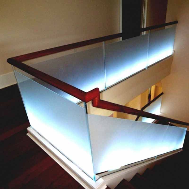 Glastreppe mit Metallgeländer in einem hell erleuchteten, modernen Haus; hellblaugrüne Glasstufen.