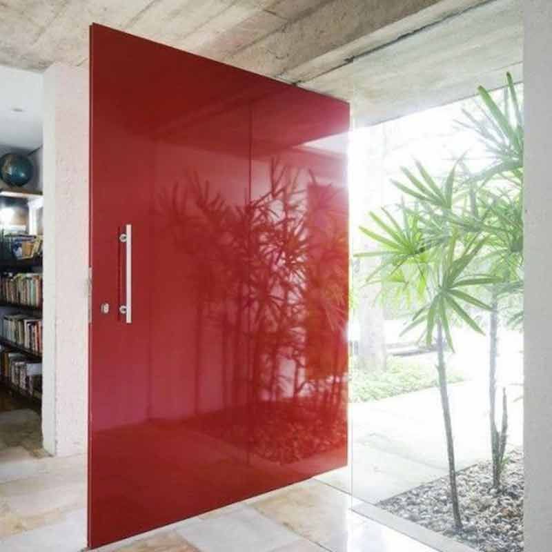 Eine große rote Tür steht einen Spalt breit offen und spiegelt Bambus. Die Tür hat einen langen, silbernen Griff.