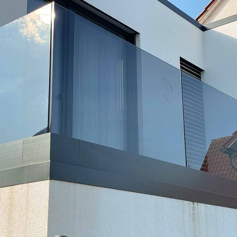 Eine große rote Tür steht einen Spalt breit offen und spiegelt Bambus. Die Tür hat einen langen, silbernen Griff.