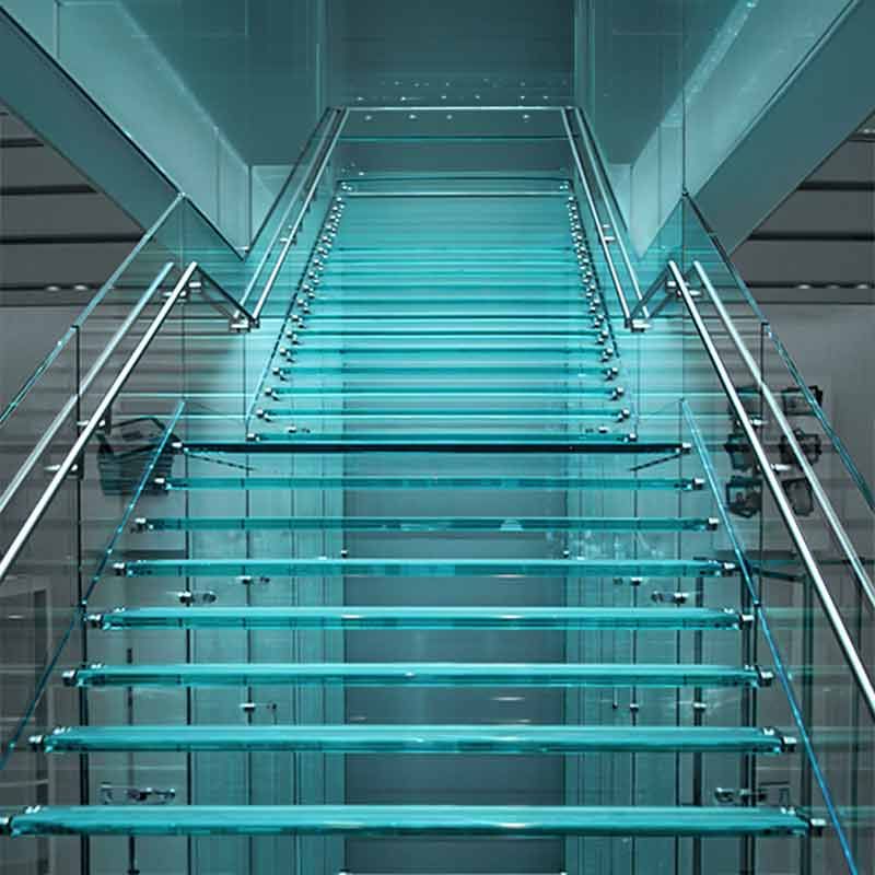 Glastreppe mit Glasstufen und Metallhandläufen.