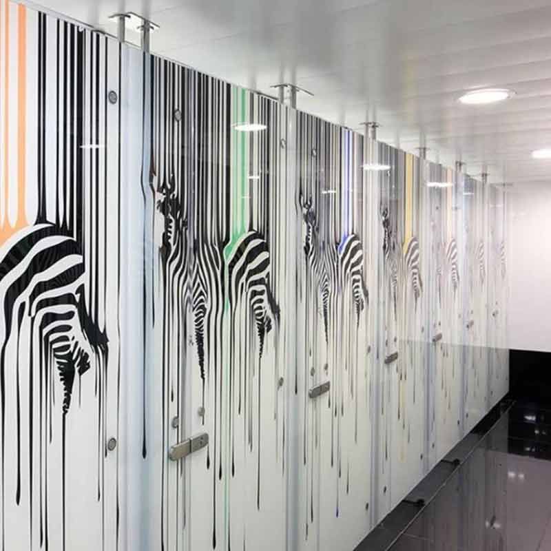 Schiebetür aus Glas mit mattierten horizontalen Paneelen und Edelstahlbeschlägen, die einen Raum mit Möbeln und einer Pflanze freigibt.