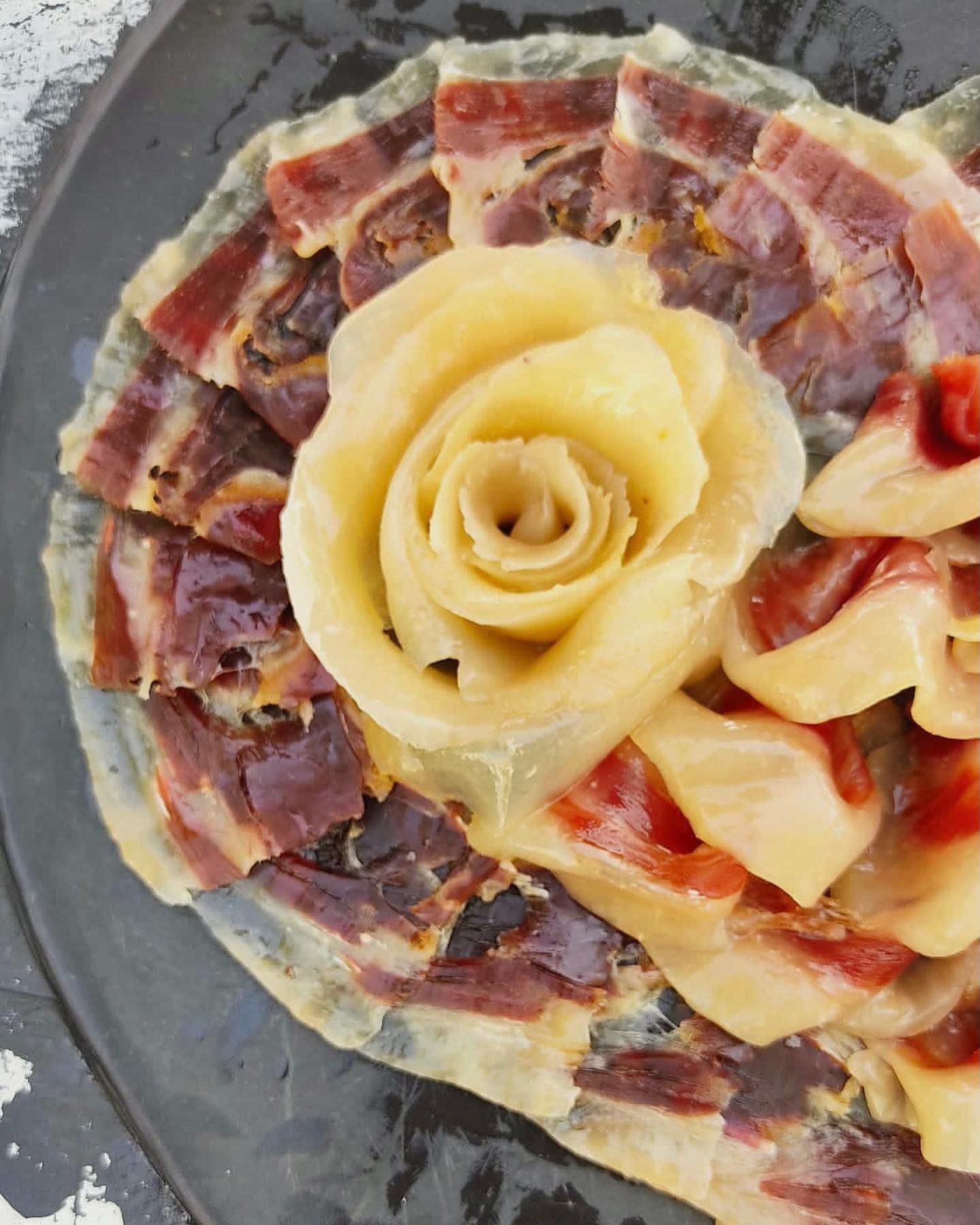 Un primer plano de una pizza con una rosa amarilla encima.