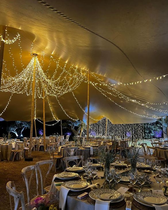 Una gran carpa con mesas y sillas preparada para una recepción de boda.