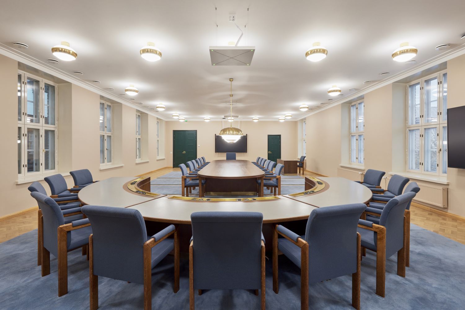 Soikea kokoushuone, jossa on siniset tuolit suuren pöydän ympärillä ja ikkunat.