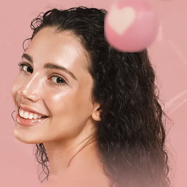 Una mujer sonríe con un corazón rosa en el cabello.