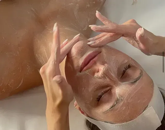 Una mujer está recibiendo un tratamiento facial con una mascarilla en la cara.