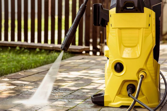 Un nettoyeur haute pression jaune est utilisé pour nettoyer un patio.