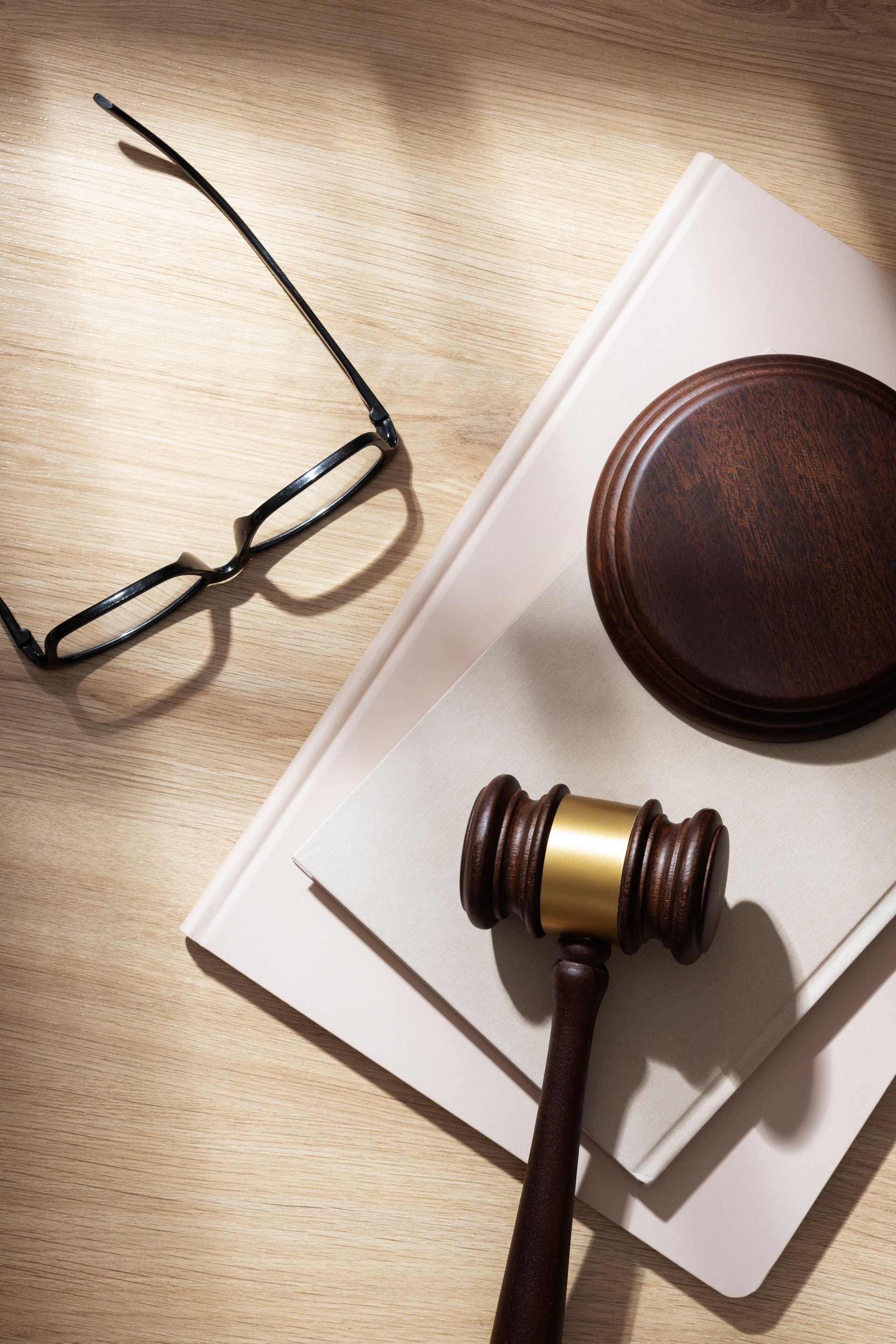 El mazo de un juez está encima de un libro junto a un par de gafas.