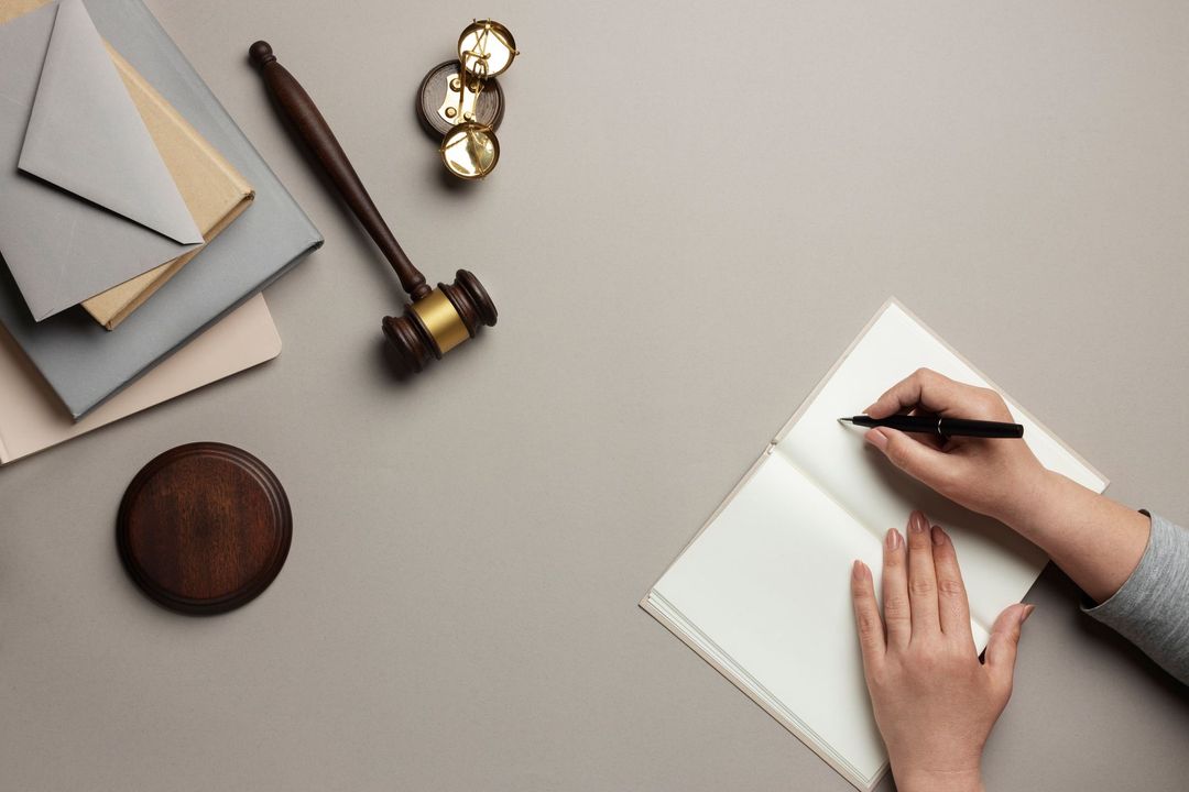 Una persona está escribiendo en un cuaderno al lado del mazo de un juez.