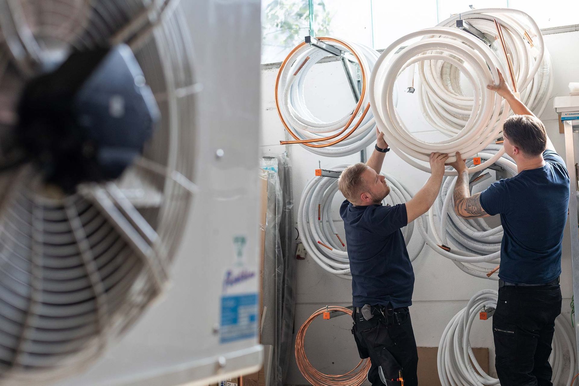 Zwei Männer arbeiten in einem Raum an einem Ventilator.