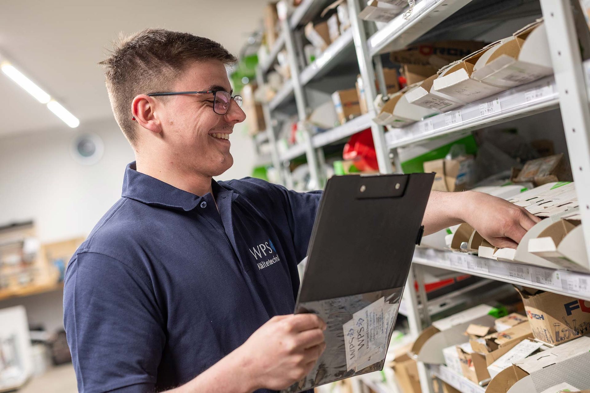 Ein Mann hält in einem Lagerhaus ein Klemmbrett.