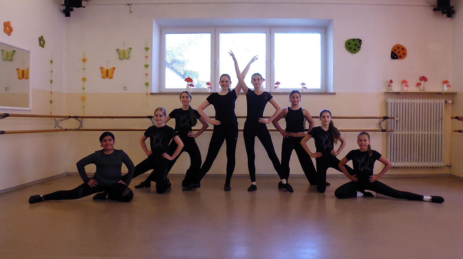 Kinder posieren in einem Tanzstudio, ausgewogen in einer spielerischen Gruppenformation.
