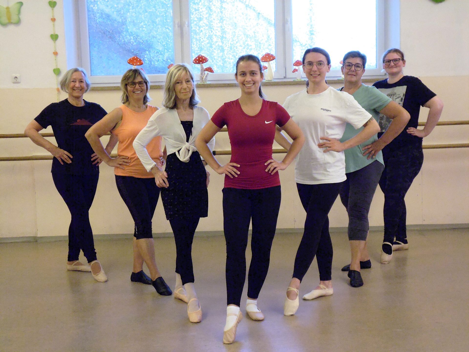 Eine Gruppe von Menschen posiert in farbenfroher Sportkleidung in einem Tanzstudio.