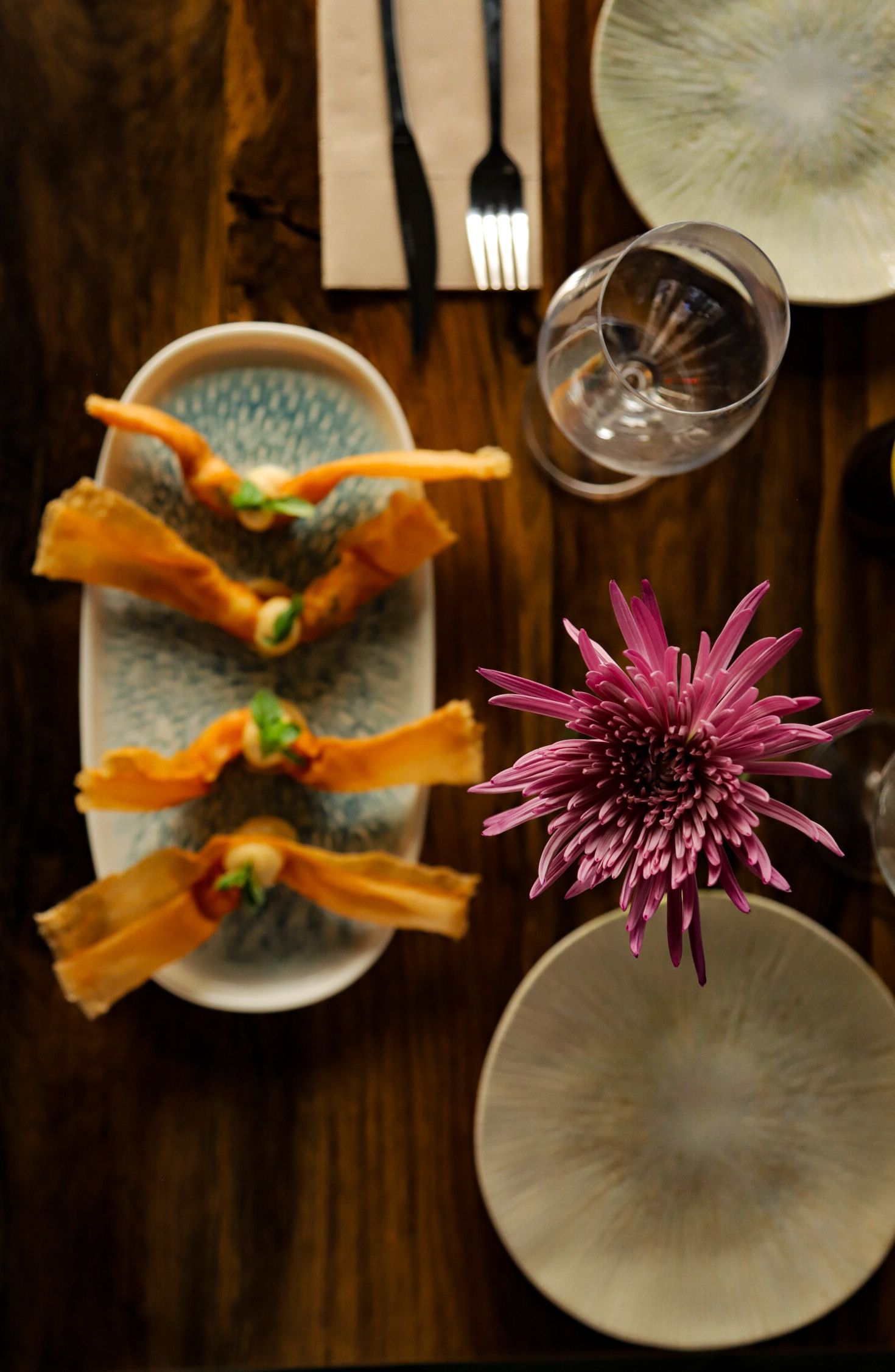 Un plato blanco con carne y verduras junto a una copa de vino.