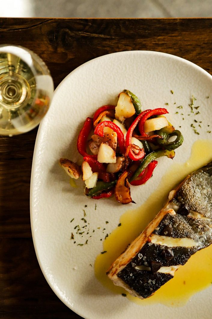 Un plato blanco cubierto con un trozo de carne y patatas.