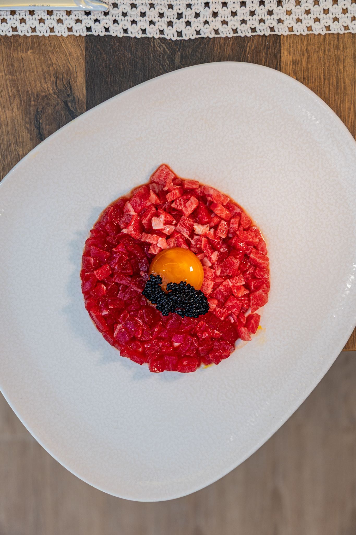 Un plato de comida y una copa de vino en una mesa de madera.