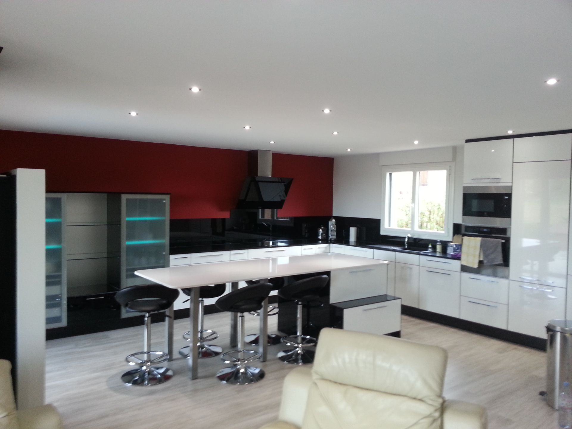 Cuisine moderne avec armoires blanches, mur d'accent rouge, îlot central avec sièges et électroménagers intégrés