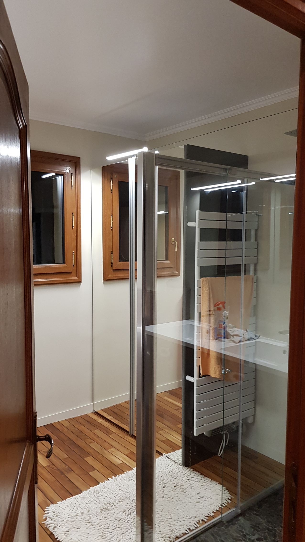 Petit couloir avec une vitrine sur un tapis blanc et un miroir encadré au mur